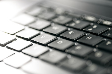Macro view of black laptop keyboard buttons against back light