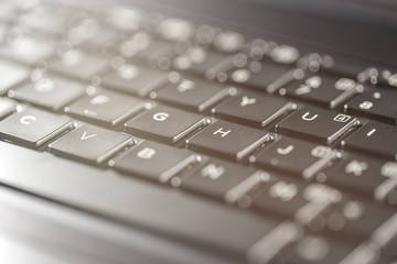 Macro view of black laptop keyboard buttons against back light