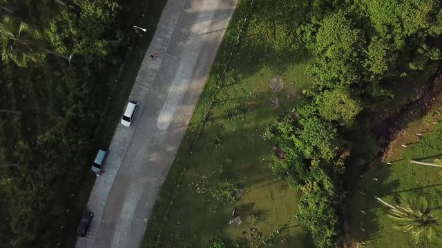 AERIAL SHOT: View of road with vehicles parks in the side. Puro and Lamba, Legazpi City, Philippines. Views of cocount trees, Mayon Volcano and the sea
