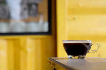 hot Americano coffee or hot black coffee in transparent cup with yellow metal sheet background. have some space for write wording