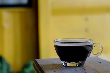 hot Americano coffee or hot black coffee in transparent cup with yellow metal sheet background. have some space for write wording