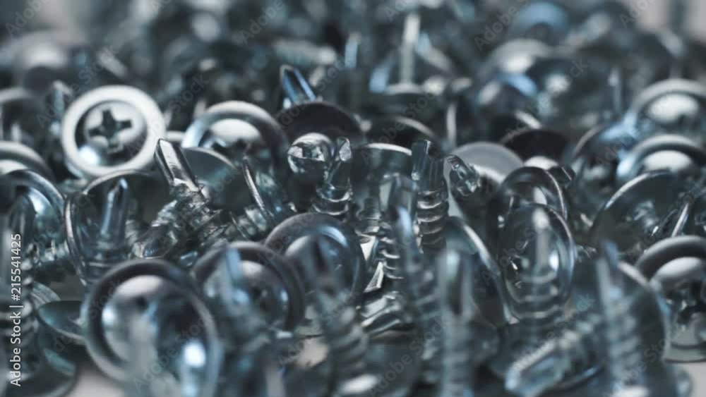 Aufkleber Macro screws rotating on a metal table and black background. Seamless loop.