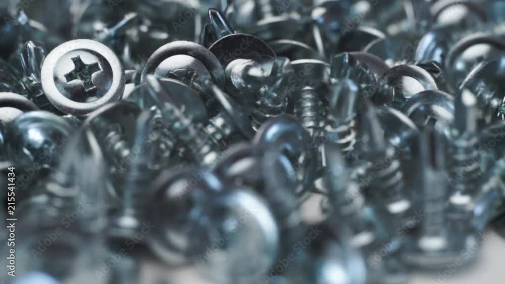 Aufkleber Macro screws rotating on a metal table and black background. Seamless loop.