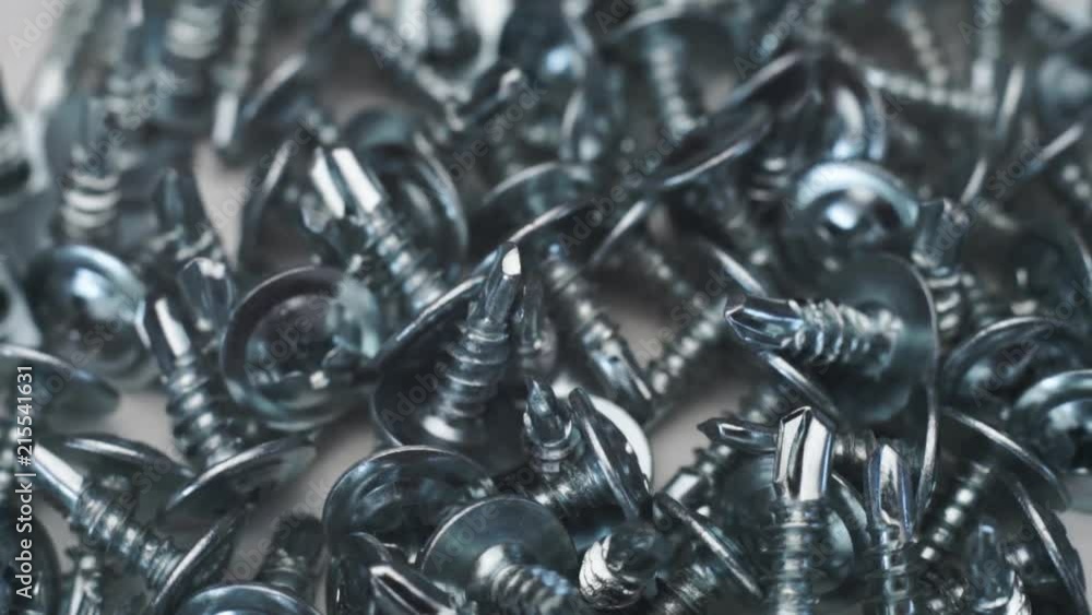 Aufkleber Macro screws rotating on a metal table and black background. Seamless loop.