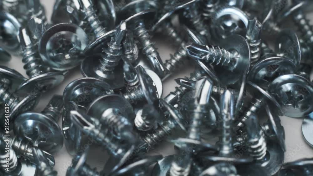 Aufkleber Macro screws rotating on a metal table and black background. Seamless loop.