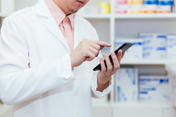 Pharmacist, Physician using a mobile phone at drugstore room. Doctor touching a cell phone in...