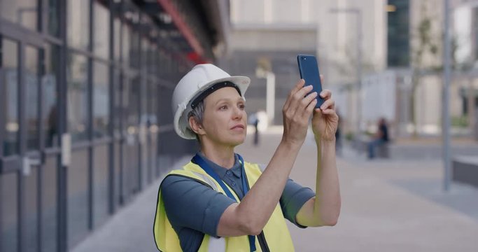 portrait senior construction engineer woman using smartphone taking photos working on site planning engineering project wearing safety helmet slow motion professional career