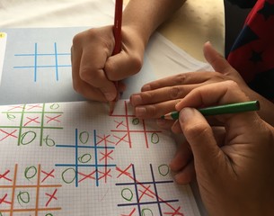 Mum and kid playing tic tac toe in travel