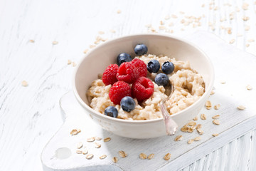 homemade oatmeal with berries on white wooden table
