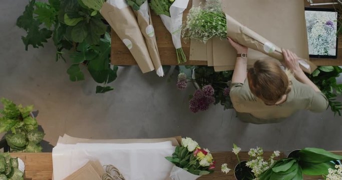 successful business woman florist wrapping beautiful bouquet preparing sales order in flower shop colleagues working together top view