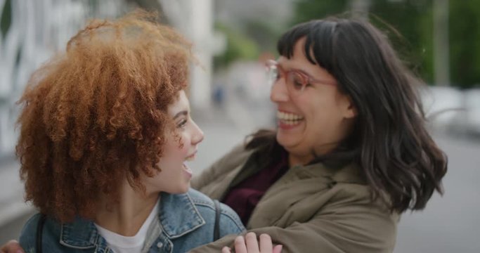 portrait of happy woman surprise kiss hugging friend diverse friends embracing enjoying friendship together in urban city street background slow motion