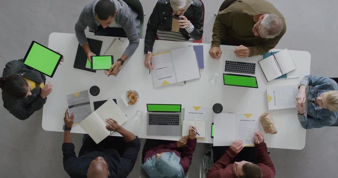 multi ethnic business people brainstorming innovative ideas for startup company viewing green screen using mobile computer technology in boardroom meeting overhead
