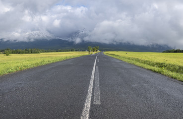 Fototapeta na wymiar asphalt road leading to cloudy mountains, concept of travel and adventure