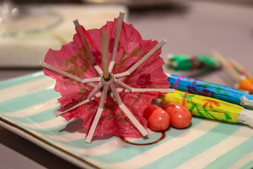 Party time - blurred Paper Cocktail Umbrellas on a tray with a couple jelly beans - close-up - selective focus