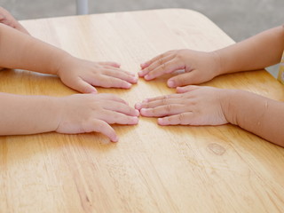 Little baby sisters placing their hands together on a table - symbolizing doing thing, playing, growing up together