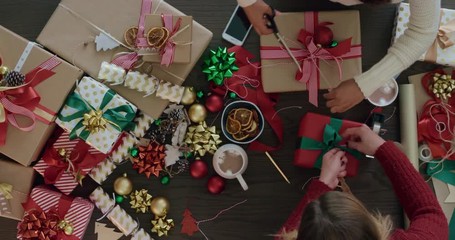 young women wrapping christmas gifts using vibrant colorful paper multi ethnic friends wrap presents festive decorations for holiday celebration top view - Powered by Adobe