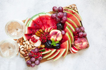 Fruit salad with watermelon, plum, peach, red currant, grape on wooden tray over white background
