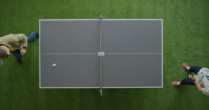 two young men playing ping pong game enjoying competitive sport in modern recreational workspace top view