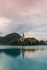 Fototapeta na wymiar Bled lake with the island and church. Blue water and storm clouds.
