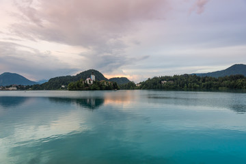 Bled lake with the island and church. Blue water and storm clouds.