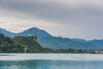 Bled castle after the storm. Dark grey sky with clouds above the Bled lake.