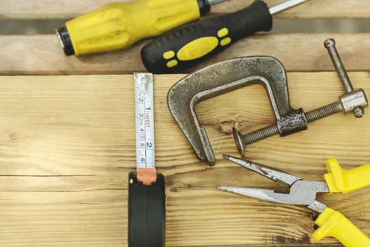 Assorted tools aranged on a wooden bench in yellow color