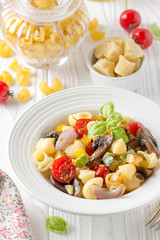 Italian pasta with fried vegetables and mushrooms, zucchini, cherry tomatoes, champignon, cheese and Basil. White plate