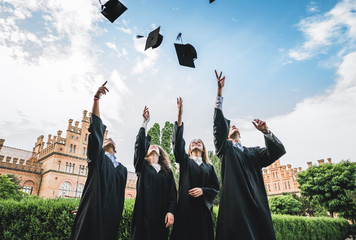 Fototapeta We've finally graduated!Graduates near university are throwing up hats in the air. obraz