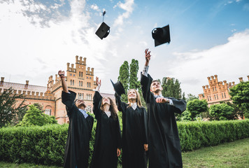 It feels amazing to finally graduate!Four happy college graduates in graduation gowns throwing...