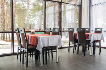 Dining tables and chairs in the restaurant. Big windows. Light interior