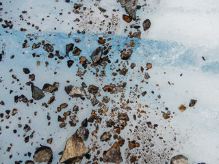 Rocks and blue ice are exposed on the surface of a melting glacier in Alaska.