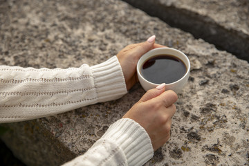 Coffee in a white cup. A cup of coffee in the hands of a girl. A cup of coffee is close-up.