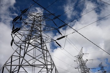 Steel electrical grid tower and overhead power supply lines against blue sky and clouds in Colombia, South America.	