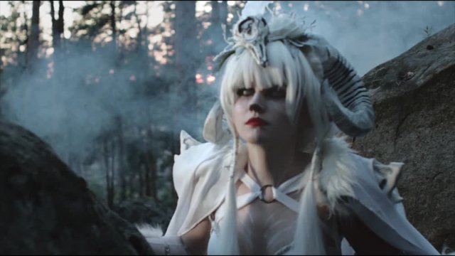 Girl dressed in costume of terrifying satyr character is creeping in woodland. She is looking around in magical mist and smoke