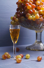 glass of young wine with grapes blue background - vintage