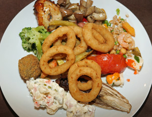 mixed dish with onion rings, chicken wings in a self-service res