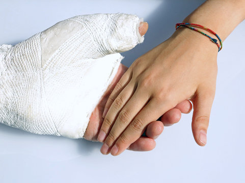 man with his hand plastered holds the hand of his daughter