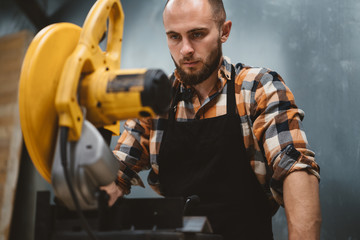 Fototapeta na wymiar Strong bearded worker use angular grinding machine in metalworking. Work in service station