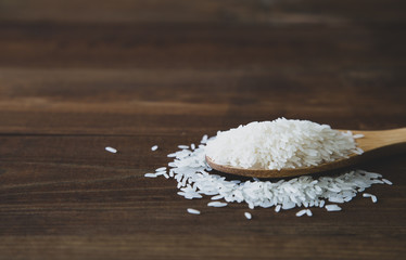 Fototapeta na wymiar White jasmine rice with wooden spoon on wooden background