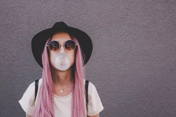 Fotobehang Young hipster woman with long pink hair blowing a bubble with bubble gum. © fedorovacz