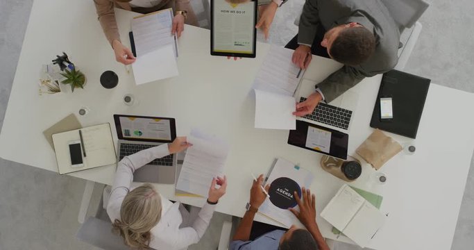professional multi ethnic business team sharing ideas in boardroom meeting brainstorming corporate strategy using market statistics in documents top view