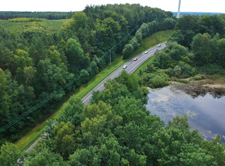 Aerial view on road, lake with reflections and forest