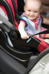 Boy sitting in a car in safety chair. focus on a hand