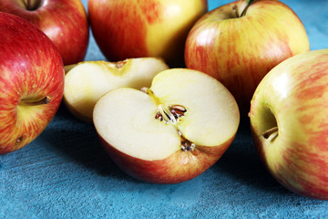 Ripe red apples with leaves on wooden background.