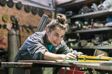young woman working in workshop - obrazy, fototapety, plakaty