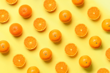 Fruit pattern of fresh orange slices on yellow background. Top view. Copy Space. Pop art design, creative summer concept. Half of citrus in minimal flat lay style.
