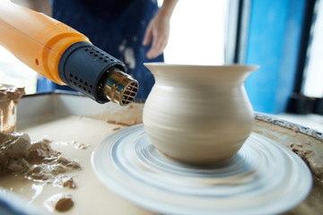 Electric device for drying clay held by potter by jug rotating in pottery wheel