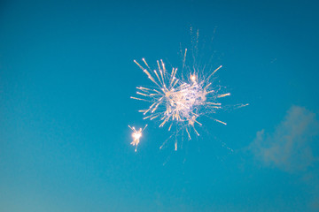 Celebratory fireworks against blue sky.