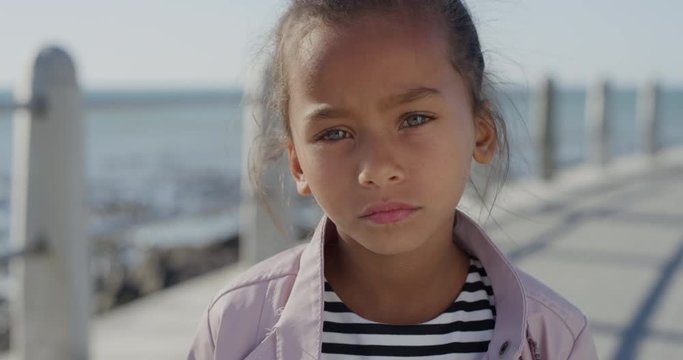 portrait young little mixed race girl looking serious contemplative kid on sunny seaside beach real people series