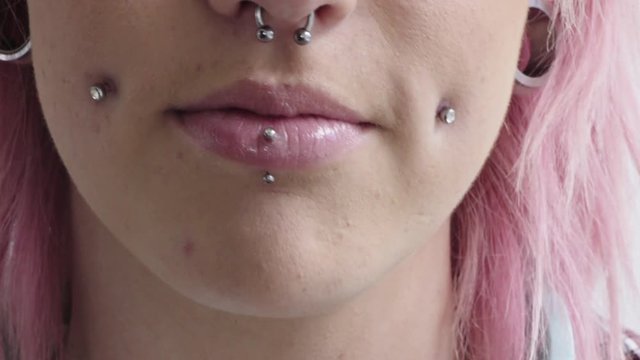 close up punk woman mouth smiling wearing piercings pink hairstyle nose ring beauty